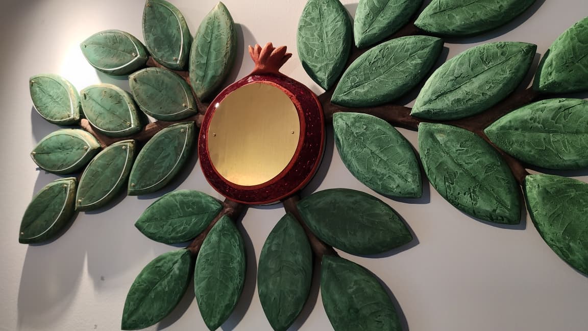 Close-up of a sculpted pomegranate donor medallion set into the branches of the Tree of Life