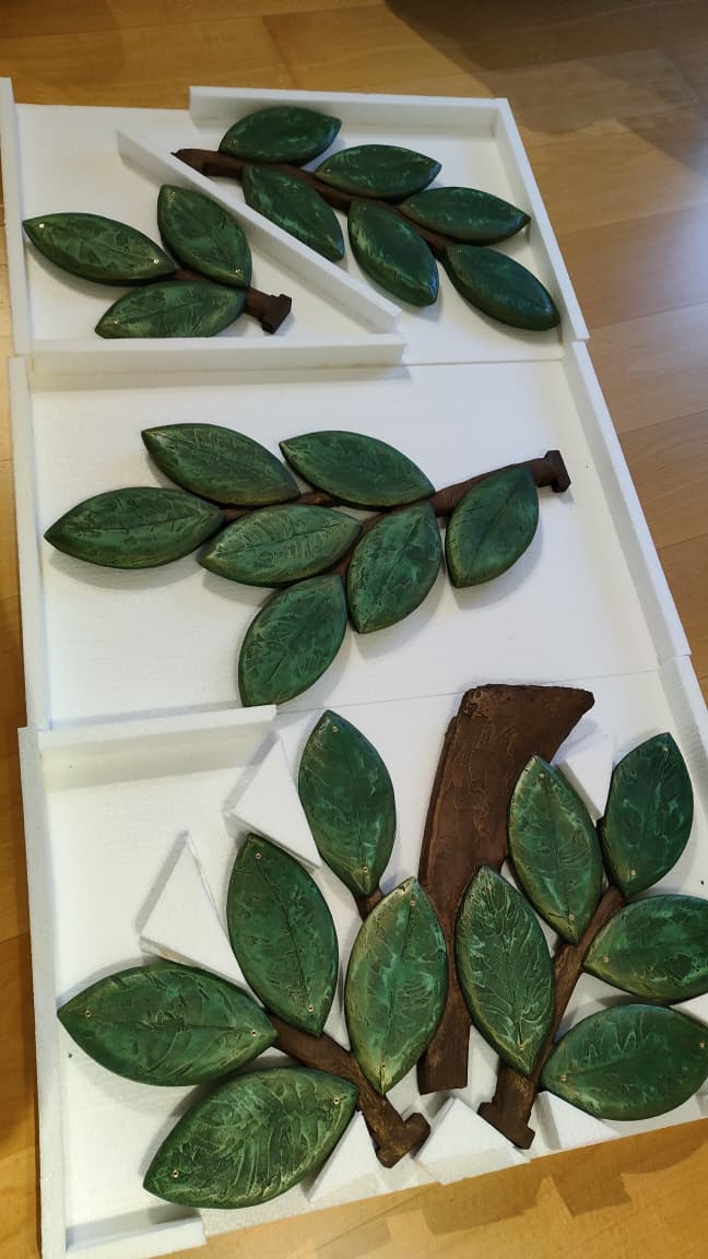 Freshly cast leaf and trunk elements before painting, laid out in the workshop